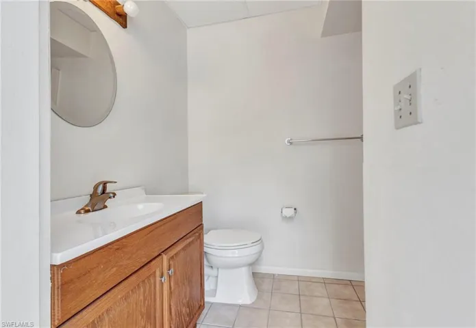 Half bath with tile patterned floors, vanity, toilet, and baseboards