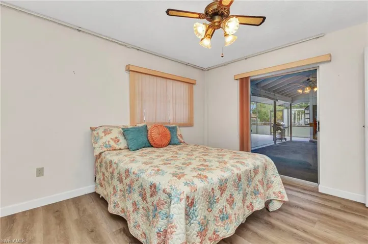 Bedroom with access to exterior, baseboards, wood finished floors, and ceiling fan
