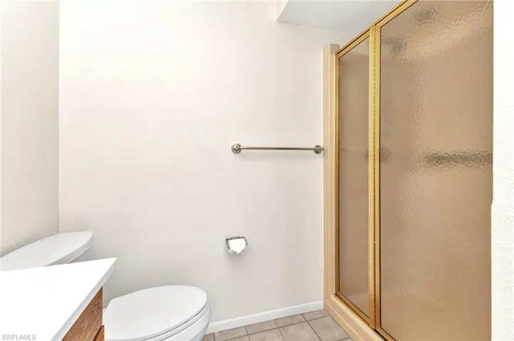 Full bathroom with a stall shower, toilet, vanity, and tile patterned flooring