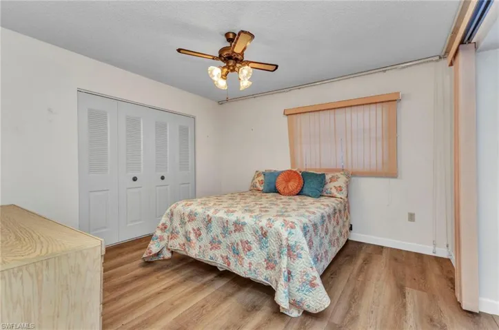 Bedroom featuring wood finished floors, a closet, baseboards, and ceiling fan
