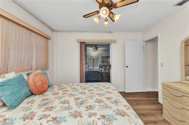 Bedroom with wood finished floors, arched walkways, ceiling fan, baseboards, and a textured ceiling