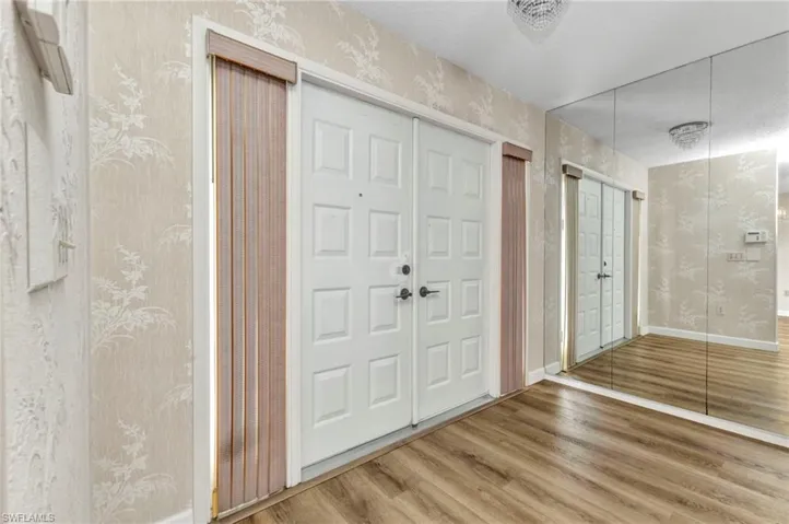 Foyer with wallpapered walls, wood finished floors, and baseboards
