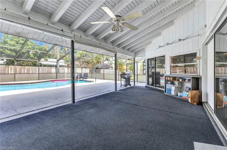 View of swimming pool featuring ceiling fan, a fenced backyard, a patio, and glass enclosure