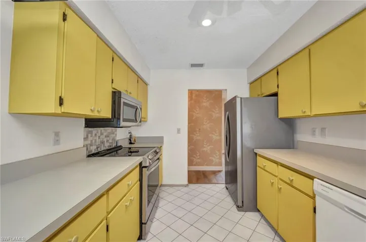 Kitchen with stainless steel appliances, baseboards, light countertops, a textured ceiling, and light tile patterned floors