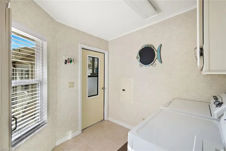 Laundry area featuring ornamental molding, independent washer and dryer, light tile patterned floors, and electric panel