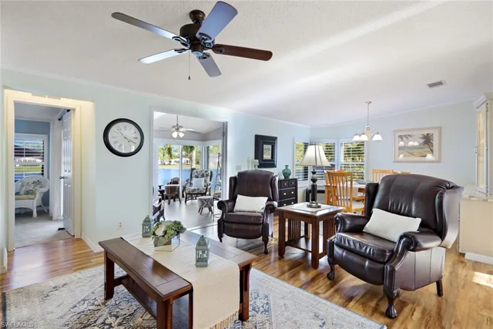 Living room with plenty of natural light, wood finished floors, ornamental molding, ceiling fan, and a textured ceiling