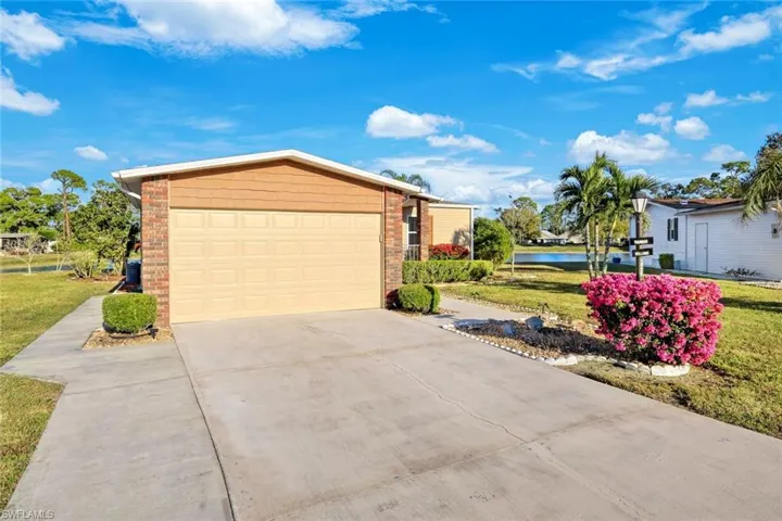 View of front of property with a front lawn, concrete driveway, and a water view