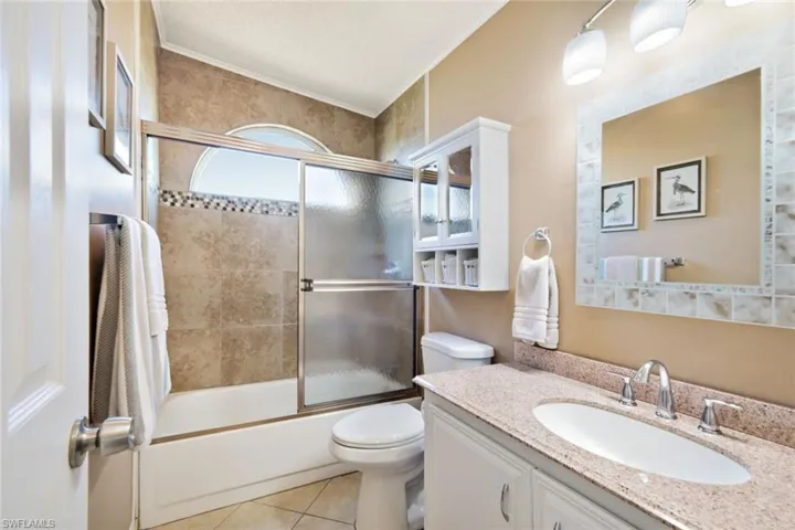 Bathroom featuring enclosed tub / shower combo, vanity, light tile patterned flooring, and crown molding