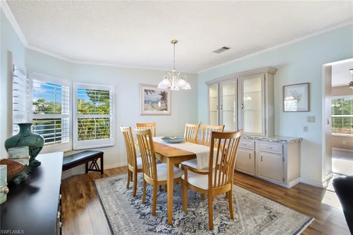 Dining area featuring ornamental molding, dark wood-type flooring, a chandelier, and a textured ceiling