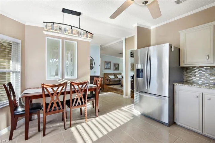 Dining area with ornamental molding, light tile patterned floors, a textured ceiling, vaulted ceiling, and ceiling fan