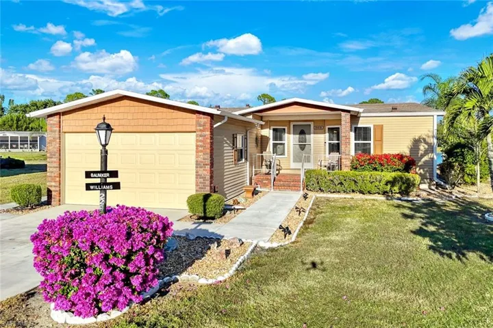 Single story home featuring a front yard, covered porch, driveway, and a garage