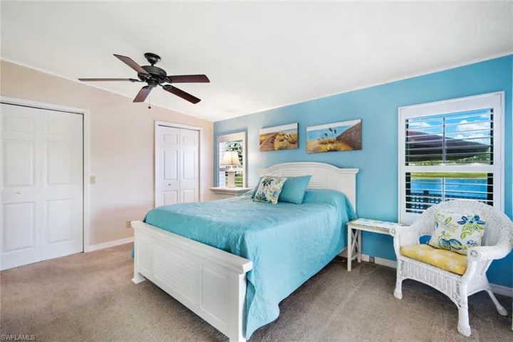 Carpeted bedroom featuring a ceiling fan and two closets