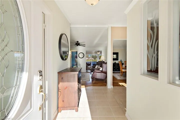 Entryway featuring ceiling fan, light tile patterned flooring, and ornamental molding