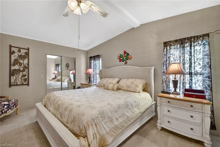 Bedroom with light carpet, a closet, ceiling fan, and a textured ceiling