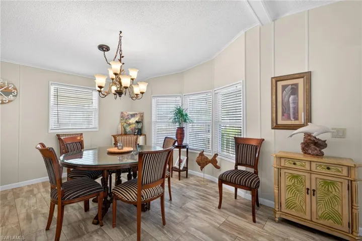 Dining space with a decorative wall, ornamental molding, a textured ceiling, a chandelier, and lofted ceiling