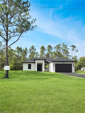 View of front facade with asphalt driveway, a garage, a front lawn, a shingled roof, and stucco siding