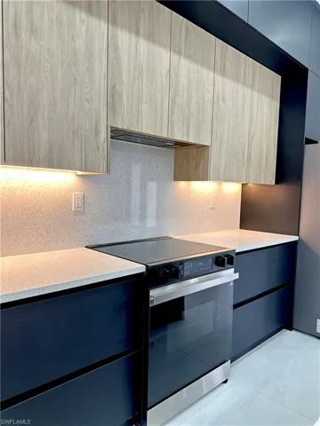 Kitchen with electric range, modern cabinets, light countertops, and extractor fan