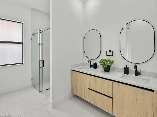 Full bathroom featuring a stall shower, tile patterned floors, and double vanity