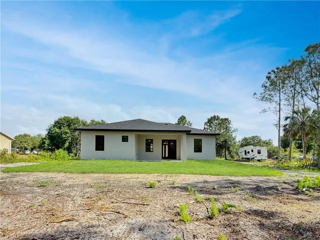 Rear view of property featuring stucco siding and a yard