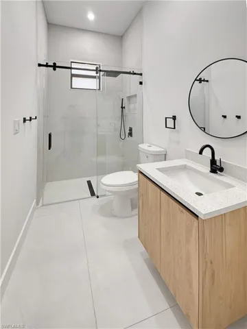 Bathroom with toilet, a stall shower, and vanity