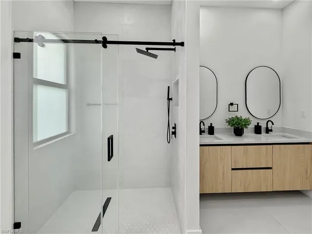 Full bathroom with double vanity and a shower stall
