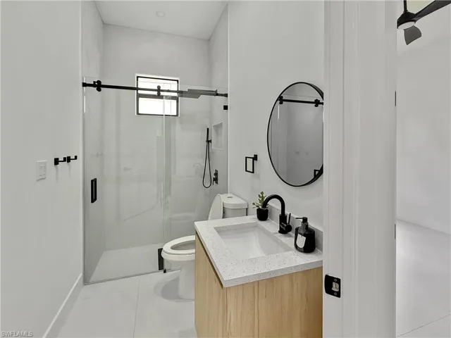 Full bath featuring toilet, a shower stall, vanity, and baseboards