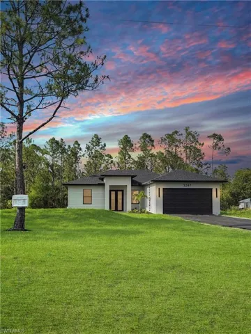 View of front of house with asphalt driveway, a garage, a front lawn, roof with shingles, and stucco siding