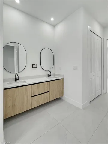 Bathroom featuring double vanity, tile patterned flooring, recessed lighting, and baseboards