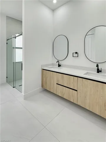 Full bathroom with double vanity, a shower stall, baseboards, and recessed lighting