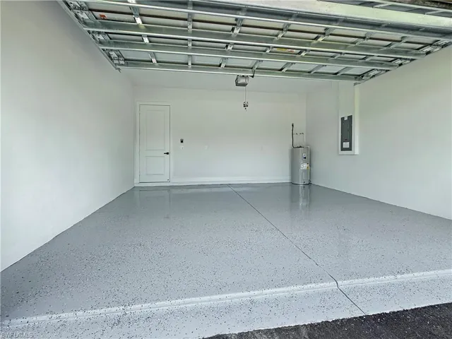Garage featuring water heater, electric panel, and a garage door opener