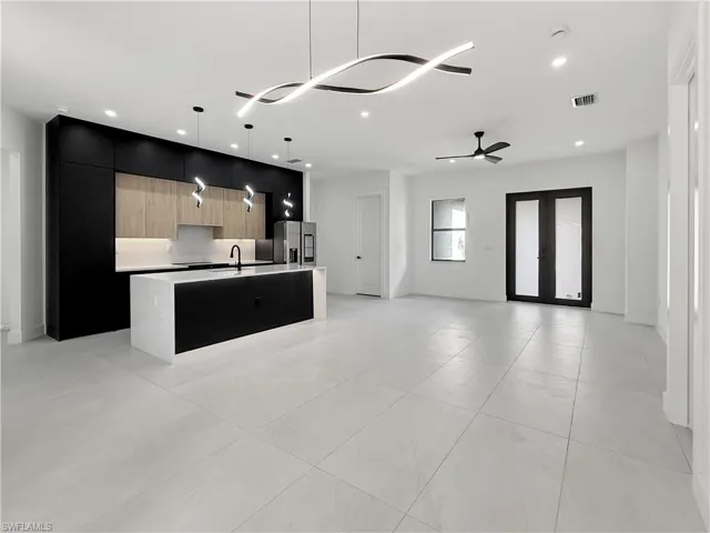 Kitchen with modern cabinets, stainless steel fridge with ice dispenser, open floor plan, a kitchen island with sink, and a sink