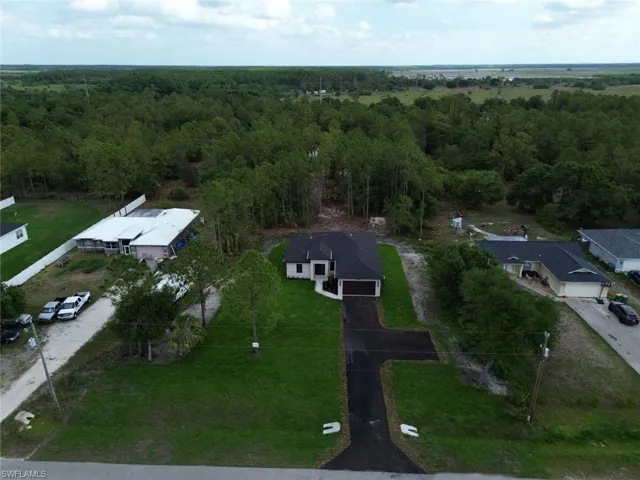 Aerial view of property and surrounding area featuring a forest