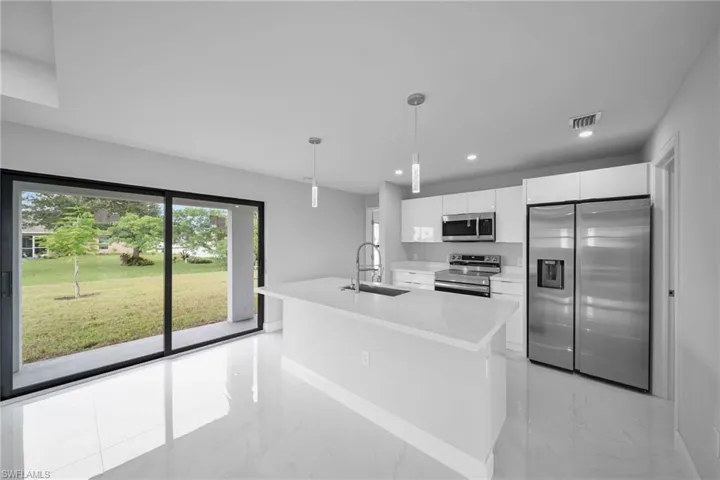 Kitchen featuring stainless steel appliances, light marble finish floors, white cabinets, light countertops, and recessed lighting
