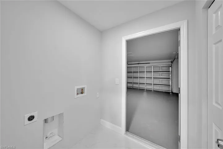 Washroom with electric dryer hookup, hookup for a washing machine, and marble finish floors