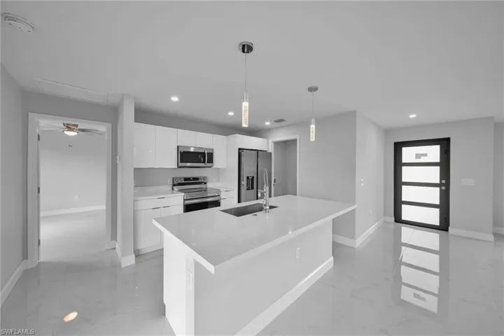 Kitchen with stainless steel appliances, light marble finish floors, white cabinetry, a kitchen island with sink, and modern cabinets