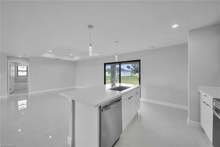 Kitchen featuring stainless steel dishwasher, modern cabinets, light marble finish floors, white cabinetry, and recessed lighting