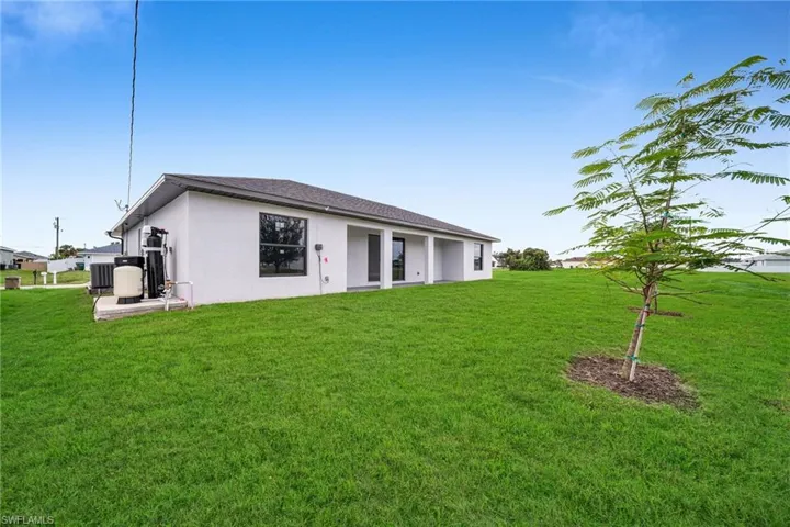 Back of property with stucco siding and a lawn