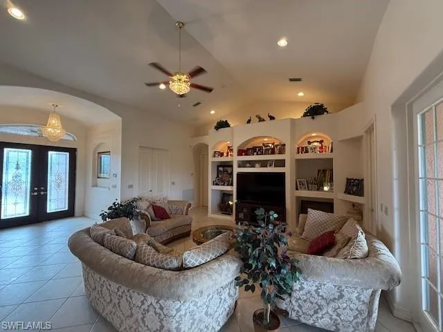 Tiled living room with french doors, vaulted ceiling, built in features, and plenty of natural light