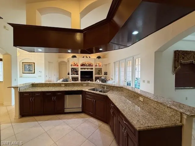 Kitchen with dark brown cabinetry, sink, dishwasher, a high ceiling, and light tile patterned flooring