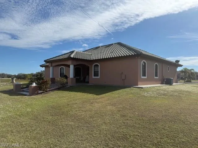 Back of property featuring a yard and central AC unit
