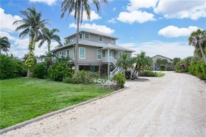 Coastal home with driveway, stairway, and a front lawn