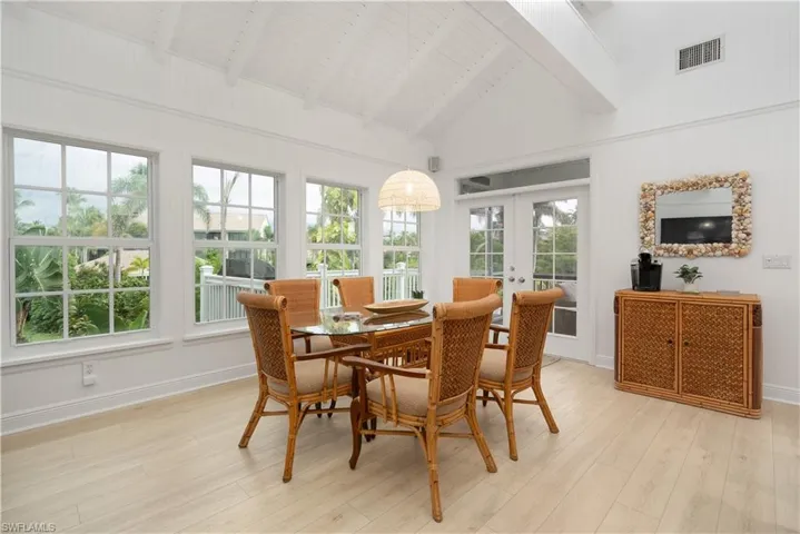 Sunroom with beam ceiling, wood finished floors, french doors, and high vaulted ceiling