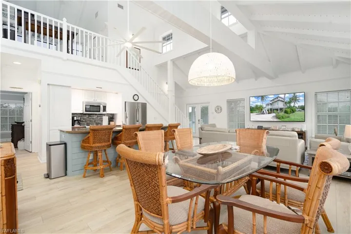 Dining area featuring light wood finished floors, stairway, a chandelier, high vaulted ceiling, and beam ceiling
