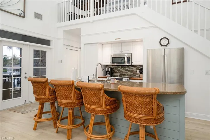 Kitchen featuring light wood finished floors, backsplash,  appliances with stainless steel finishes, and granite counters