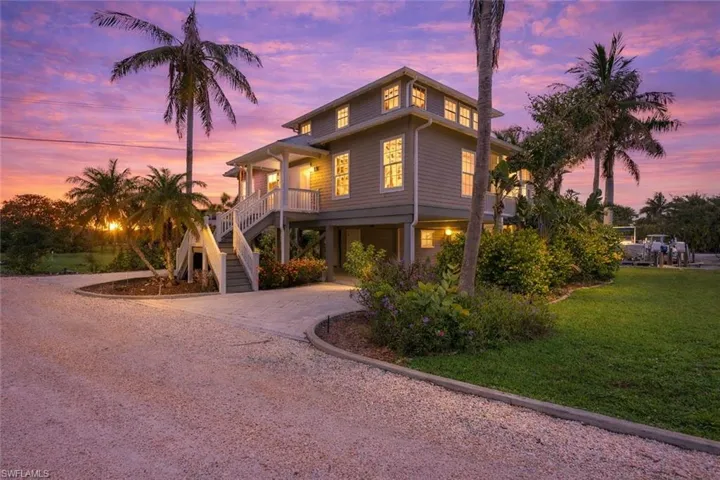 View of front of home featuring curved driveway, a lawn, and a porch