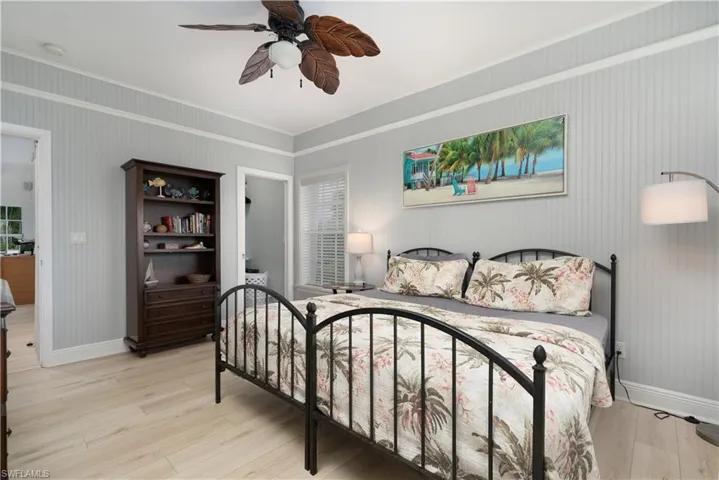 Bedroom featuring light wood-style floors, a ceiling fan, ornamental molding, and ensuite bathroom