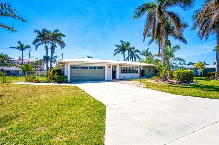Ranch-style house featuring driveway, front yard, 2 car garage, and fence 0n a triple lot