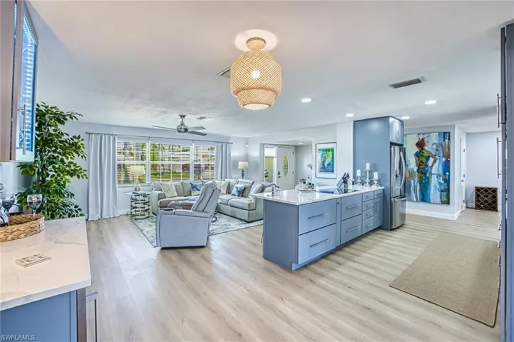 Kitchen with, a peninsula, light wood-style flooring, and stainless steel refrigerator with ice dispenser and glass cooktop