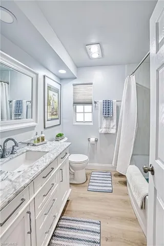 Full Guest bathroom, toilet, shower /soaking tub combo with wood finished floors, and granite vanity