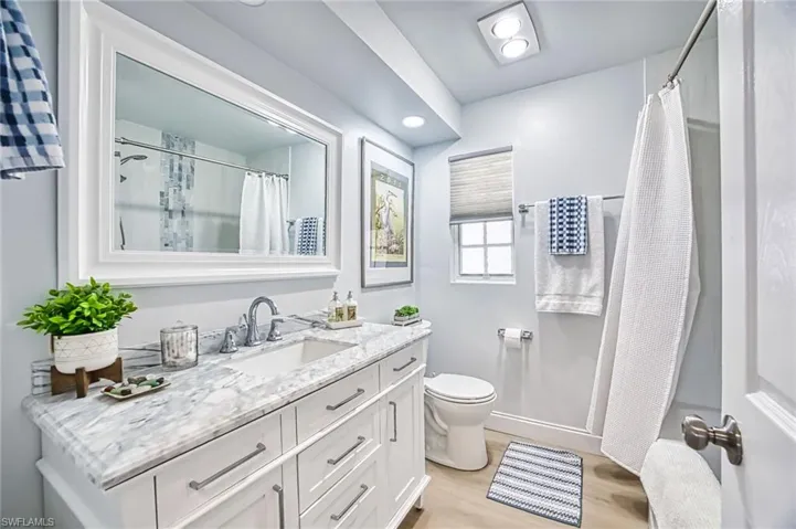 Guest bathroom featuring a shower /soaking tub combo with tiled shower walls and granite vanity